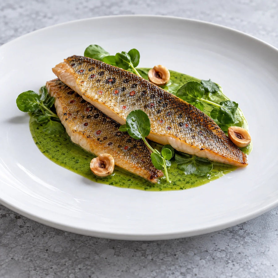 Two crisp skinned brown trout fillets with watercress sauce, hazelnuts and leaves