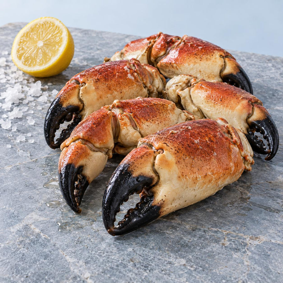Cooked brown crab claws on a grey stone slab with half a lemon and flaked sea salt