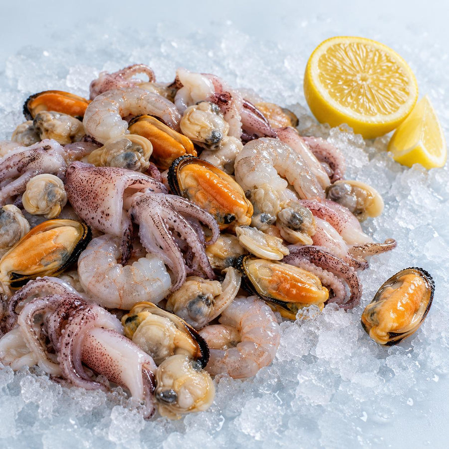 A raw seafood mix of mussels, prawns, squid and clams on crushed ice with half a lemon