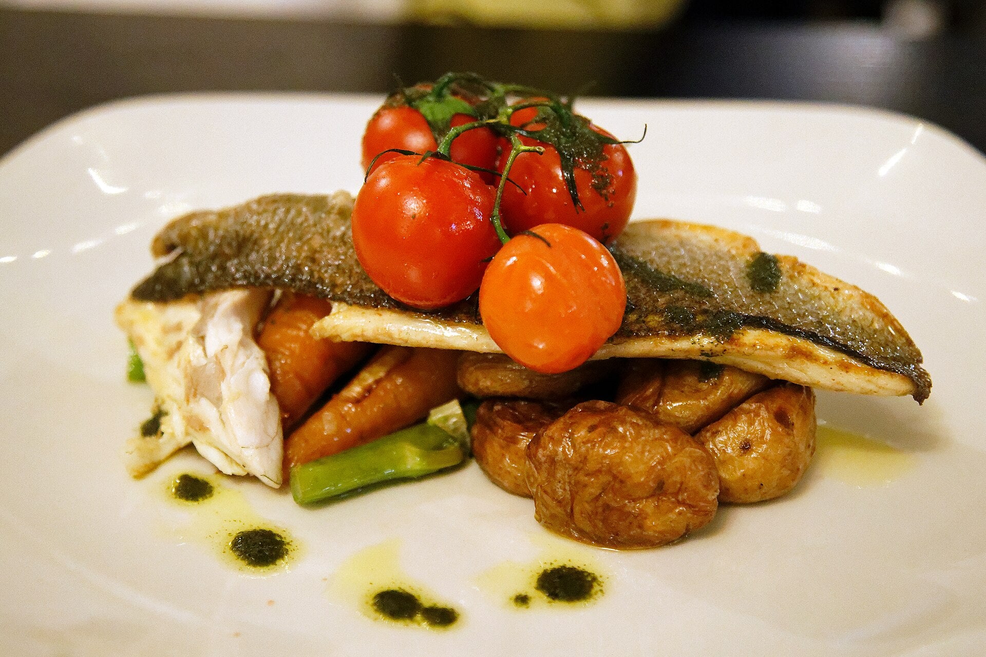Pan-seared sea bass fillets with roast vegetables on a plate