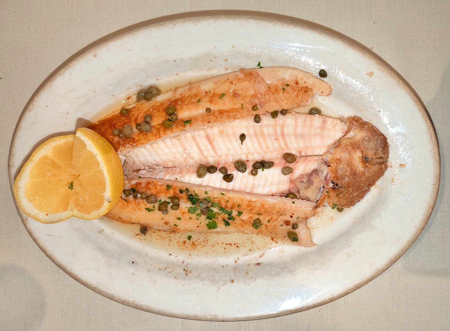 Dover sole meunière on an oval plate with capers and lemon