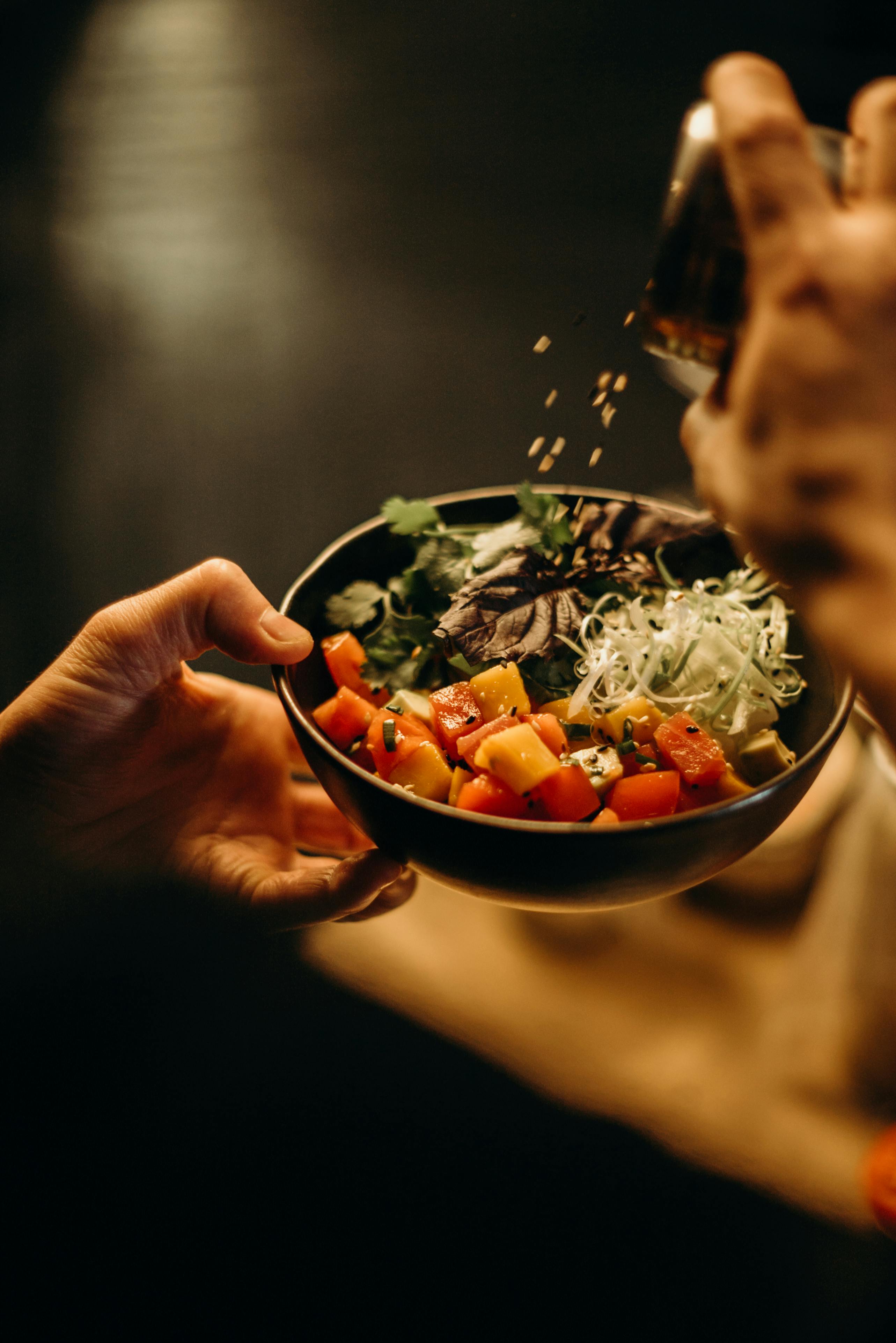 Hands holding a bowl of diced vegetables and herbs