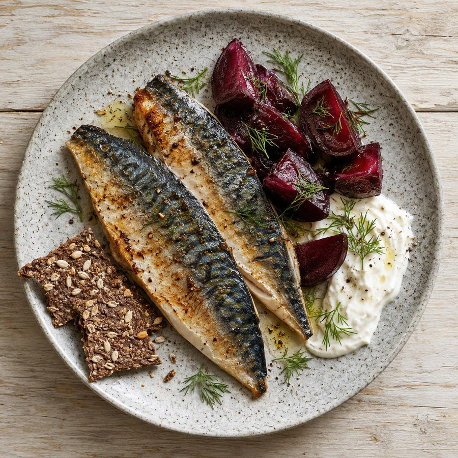 Grilled mackerel fillets on a speckled stoneware plate with roasted beetroot, white cream, dill and seeded crispbread